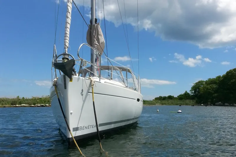 Slide: The Image of 2010 Beneteau Oceanis 31 sailboat anchored on calm water under a partly cloudy sky. - 4