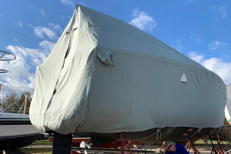 Slide: The Image of 2010 Beneteau Oceanis 31 sailboat covered, stored on land under a clear blue sky. - 9