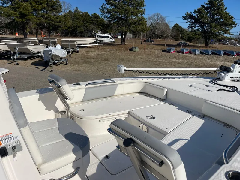 Slide: The Image of 2022 Robalo 226 Cayman boat interior with seating and storage, parked outdoors. - 16