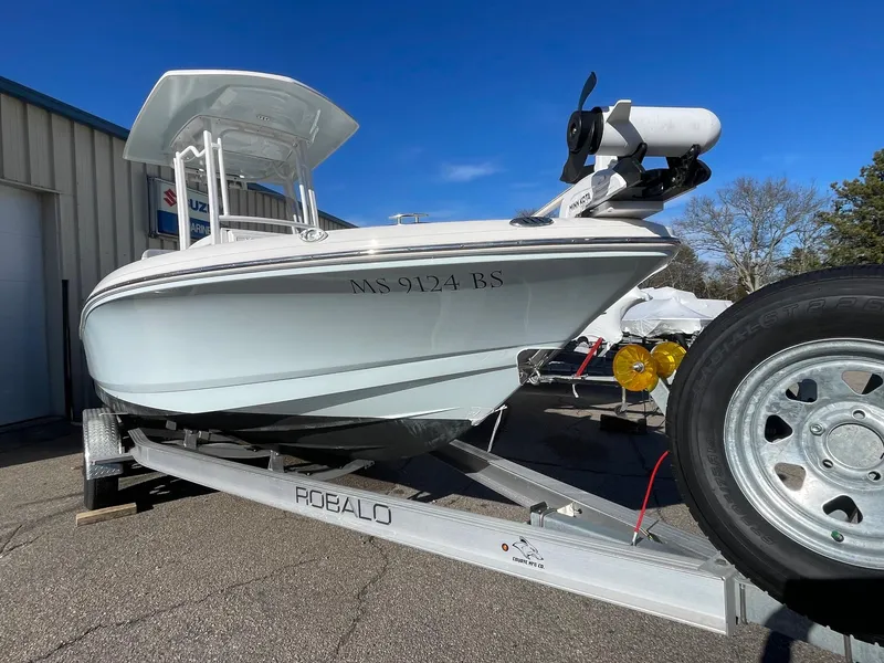 Slide: The Image of 2022 Robalo 226 Cayman boat on trailer, parked outdoors under clear blue sky. - 2