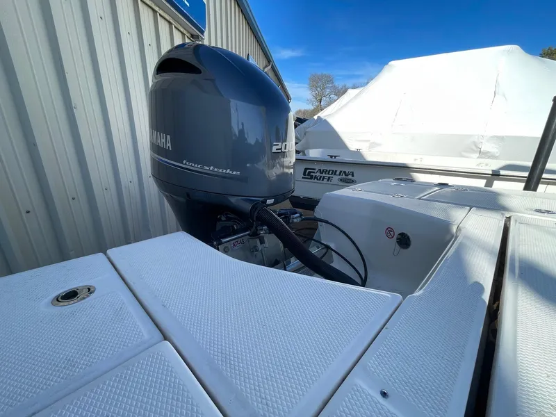 Slide: The Image of 2022 Robalo 226 Cayman boat with Yamaha 200 engine, docked near a metal building. - 7