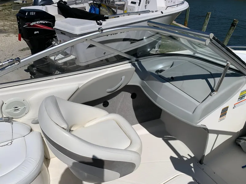 Slide: The Image of 2009 Bayliner 205 boat interior with white seating and dashboard, docked by the water. - 5