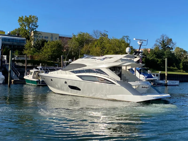 Slide: The Image of 2010 Marquis 500 Sport Bridge yacht cruising in a marina with trees in the background. - 5