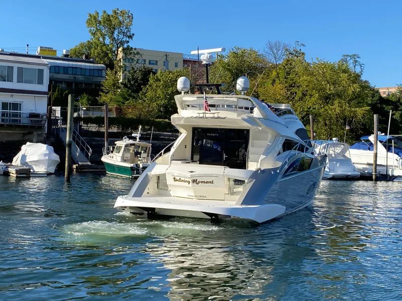 Slide: The Image of 2010 Marquis 500 Sport Bridge yacht docked in a marina, surrounded by other boats. - 7