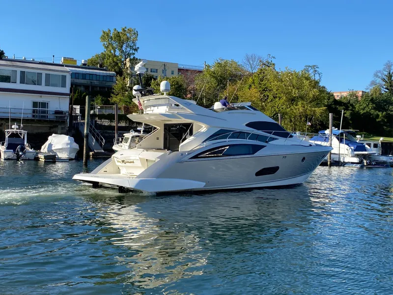 Slide: The Image of 2010 Marquis 500 Sport Bridge yacht docked in a marina, surrounded by calm water and greenery. - 8