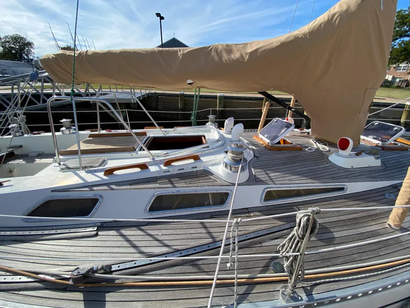 Slide: The Image of 1973 Nautor Swan 44 sailboat with wooden deck and covered sails, docked in a marina. - 22
