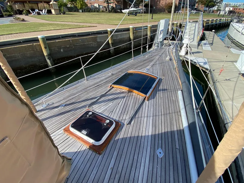 Slide: The Image of 1973 Nautor Swan 44 sailboat deck with wooden hatches, docked in a marina. - 8