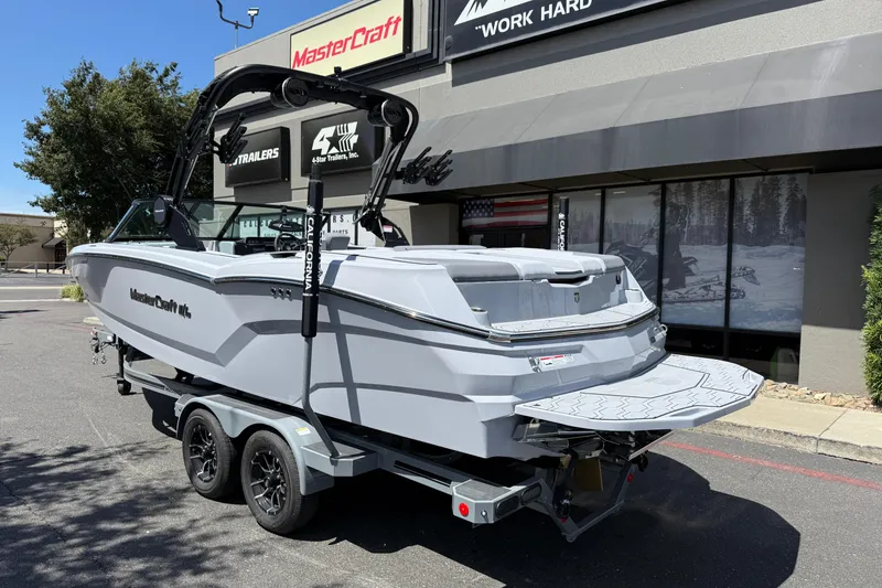 Slide: The Image of 2025 MasterCraft NXT24 boat on trailer outside dealership, showcasing sleek design and modern features. - 13
