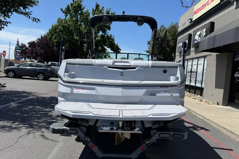 Slide: The Image of 2025 MasterCraft NXT24 boat rear view in a parking lot, near dealership. - 14