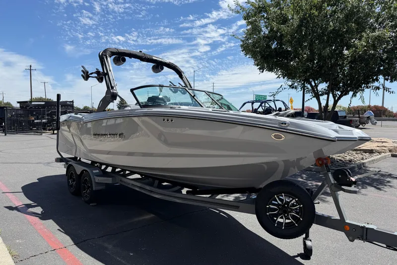 Slide: The Image of 2025 MasterCraft NXT24 boat on trailer, parked outdoors under a clear sky. - 16