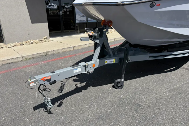 Slide: The Image of 2025 MasterCraft NXT24 boat trailer parked on asphalt near a building. - 19