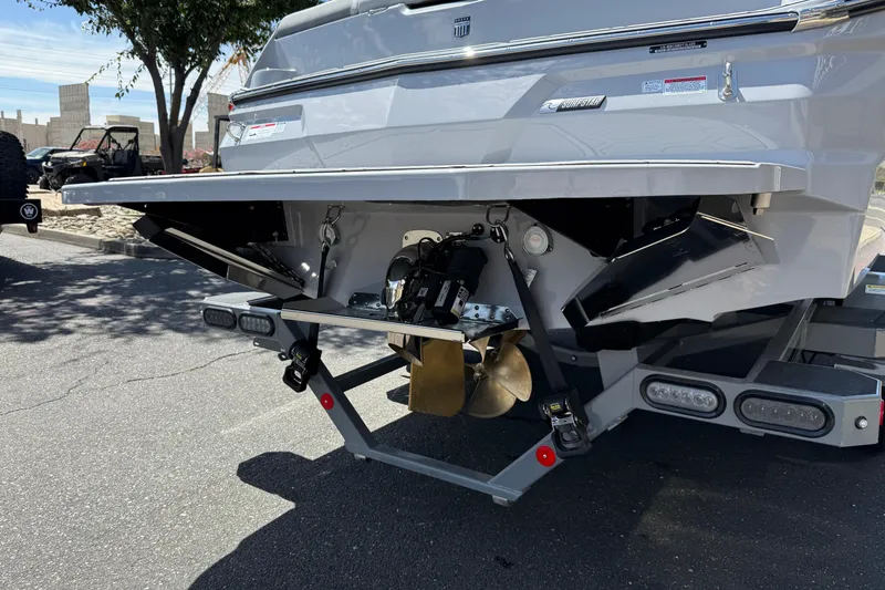 Slide: The Image of 2025 MasterCraft NXT24 boat stern with propeller and trim tabs in a parking lot. - 23