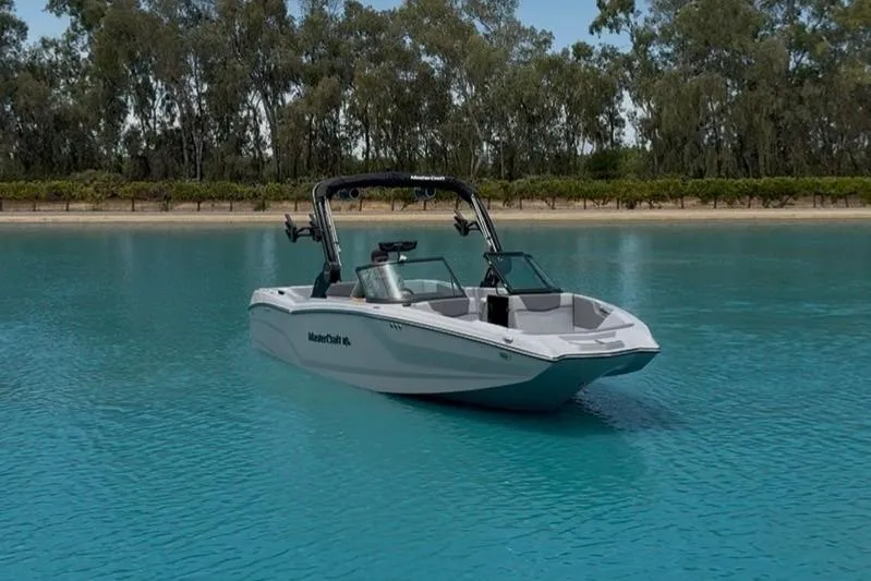 Slide: The Image of 2025 MasterCraft NXT24 boat on serene blue water with lush green trees in the background. - 5