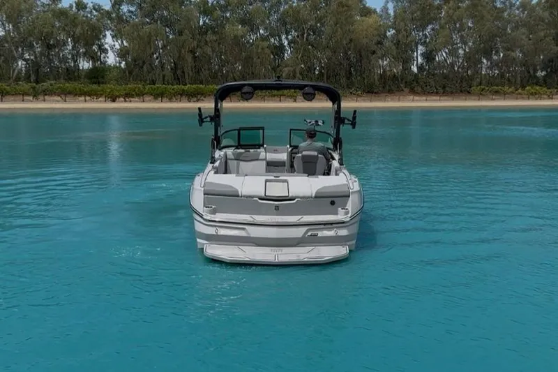 Slide: The Image of 2025 MasterCraft NXT24 boat on clear blue water, surrounded by trees. - 8