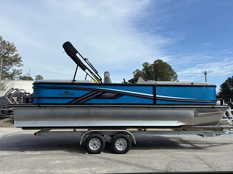 The Image of 2025 SunCatcher Fusion 324RC pontoon boat on trailer, blue and silver design. - 1