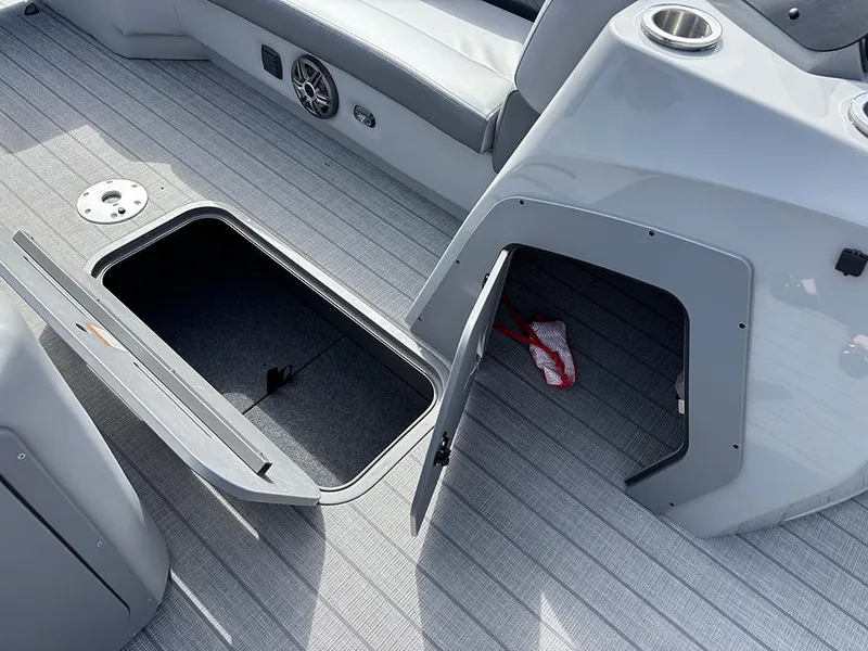 Slide: The Image of 2025 SunCatcher Fusion 324RC boat interior with open storage compartments and sleek gray flooring. - 16