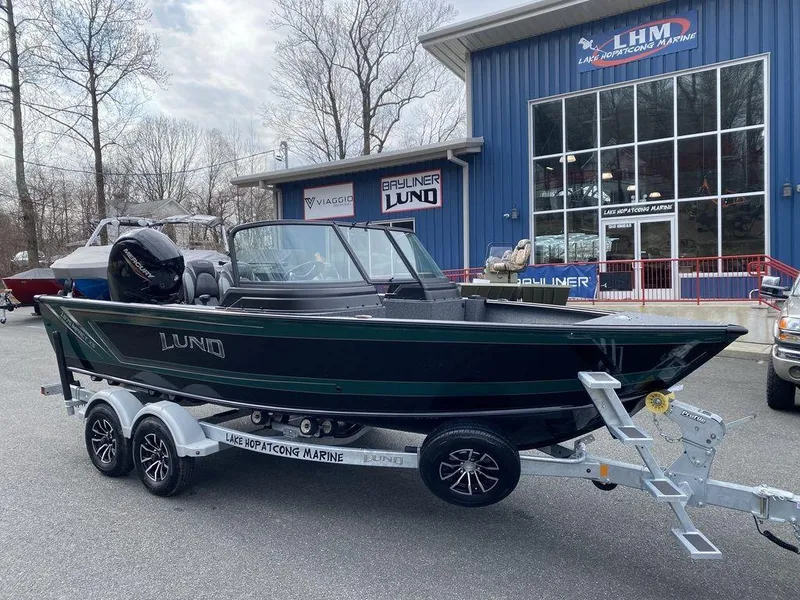 Slide: The Image of 2025 Lund 1875 Impact XS Sport boat on trailer outside marine dealership. - 13