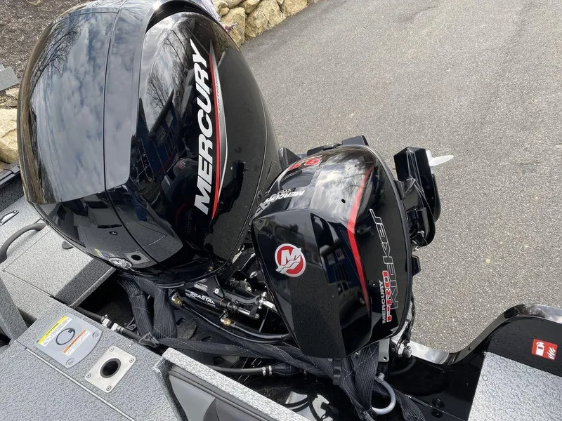 Slide: The Image of 2025 Lund 1875 Impact XS Sport with Mercury outboard motor, parked on pavement. - 5