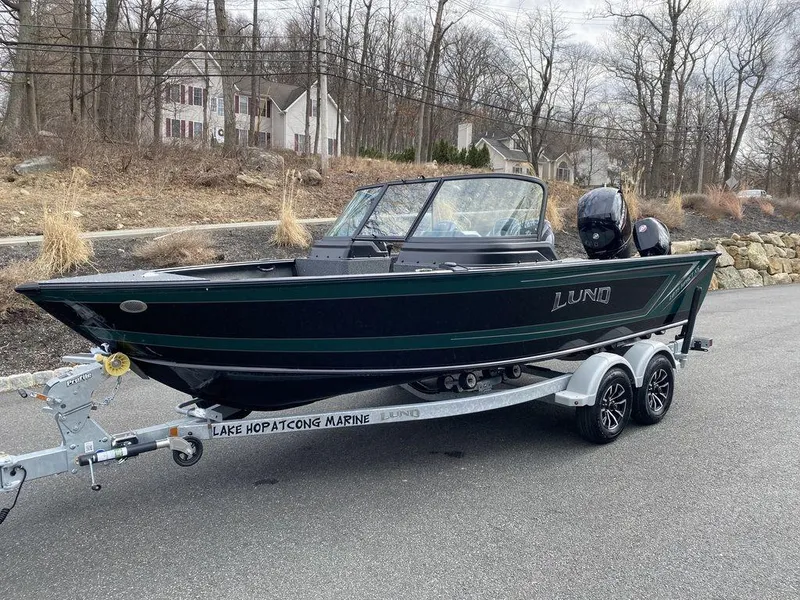 Slide: The Image of 2025 Lund 1875 Impact XS Sport boat on trailer, parked on roadside. - 6