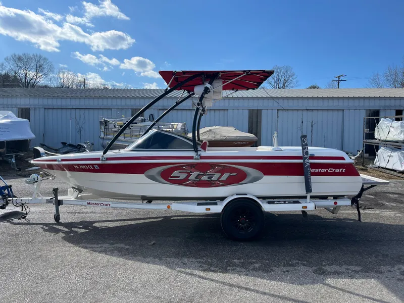 Slide: The Image of 1999 MasterCraft XStar boat on trailer, red and white design, parked outdoors. - 10