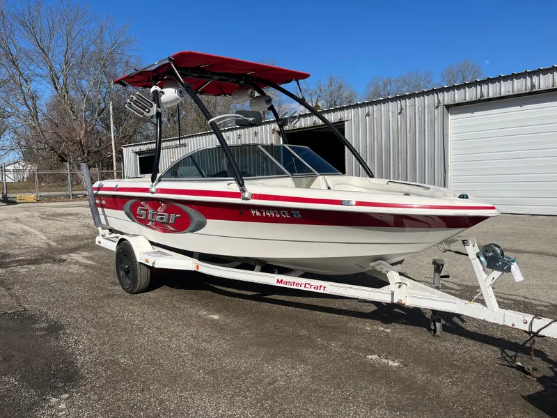 Slide: The Image of 1999 MasterCraft XStar boat on trailer, red and white design, parked outdoors. - 3