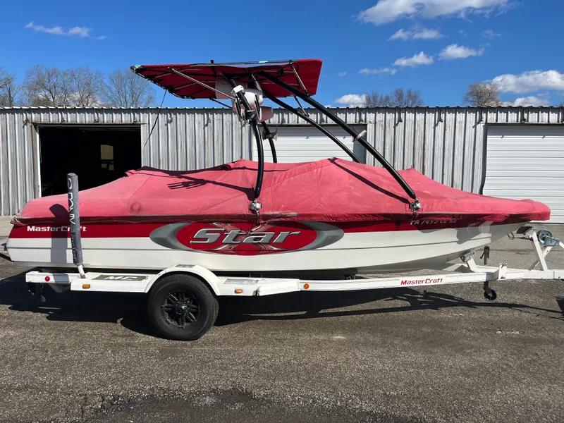 Slide: The Image of 1999 MasterCraft XStar boat with red cover and trailer, parked outdoors. - 9