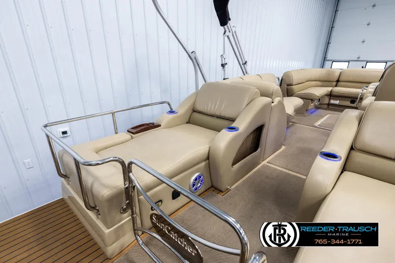 Slide: The Image of 2014 SunCatcher Elite 324 boat interior with beige seating and cup holders. - 23