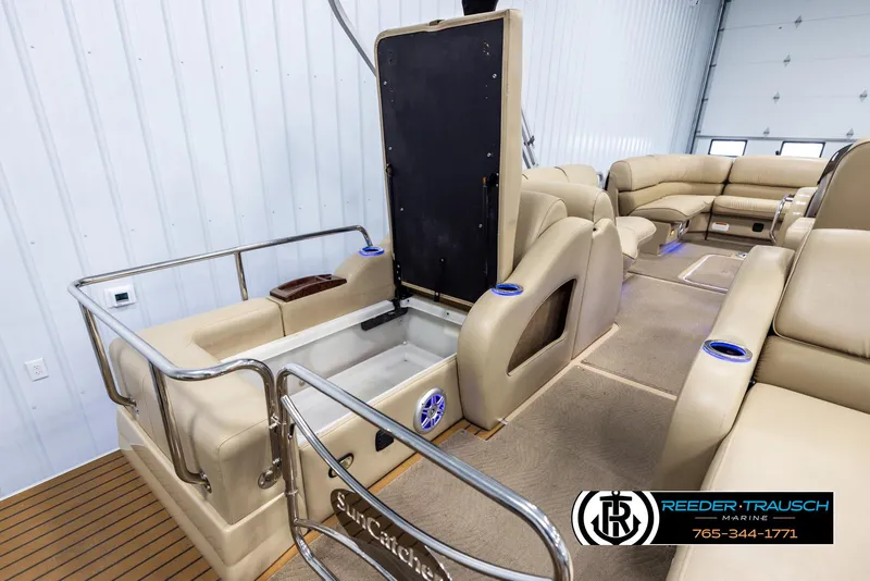 Slide: The Image of 2014 SunCatcher Elite 324 pontoon boat interior with beige seating and storage compartments. - 24