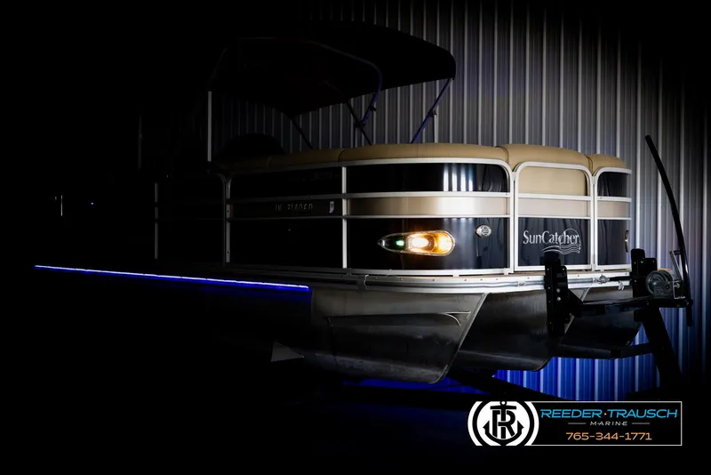 Slide: The Image of 2014 SunCatcher Elite 324 pontoon boat with illuminated side view in a dimly lit setting. - 4
