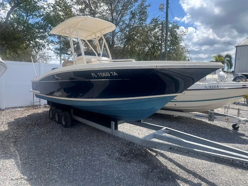 Slide: The Image of 2022 Scout 215 XSF boat on trailer, parked outdoors under a partly cloudy sky. - 0