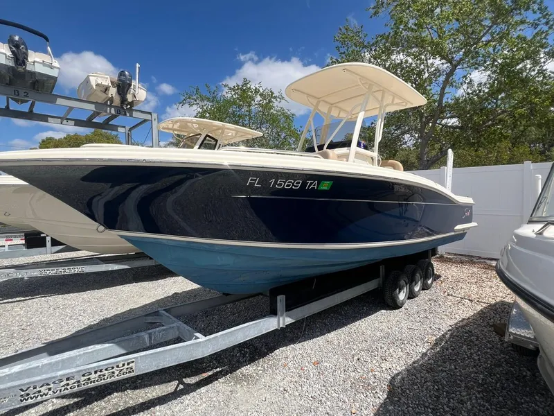 Slide: The Image of 2022 Scout 215 XSF boat on trailer, parked outdoors under clear sky. - 1
