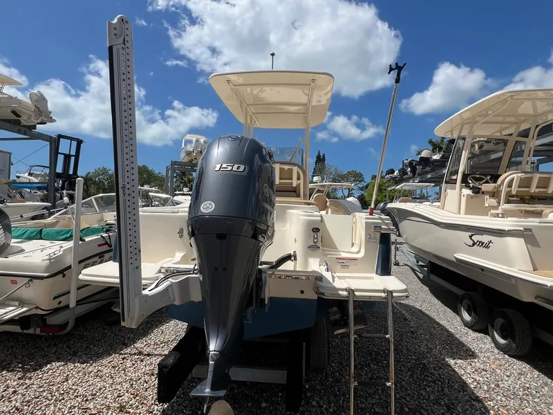 Slide: The Image of 2022 Scout 215 XSF boat with Yamaha 150 engine, parked on gravel under a blue sky. - 4
