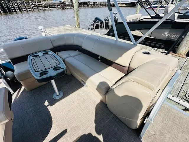 Slide: The Image of 2019 Sun Tracker Party Barge 20 DLX with beige seating and table, docked by the water. - 7