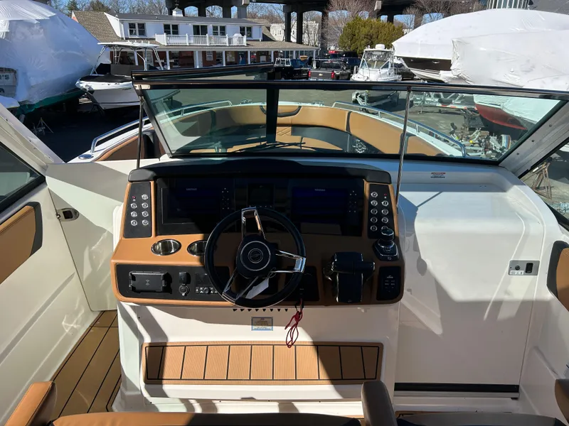 Slide: The Image of 2023 Chaparral 300 OSX boat cockpit with modern controls and tan seating. - 10