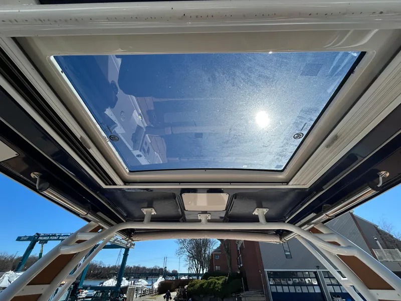 Slide: The Image of 2023 Chaparral 300 OSX boat with sunroof, showcasing clear sky and marina view. - 13