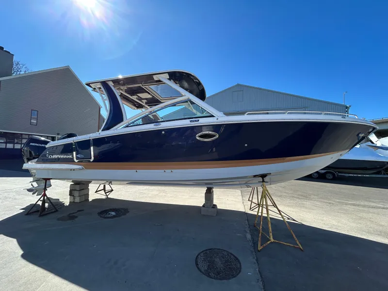 Slide: The Image of 2023 Chaparral 300 OSX boat displayed outdoors on stands under clear blue sky. - 3