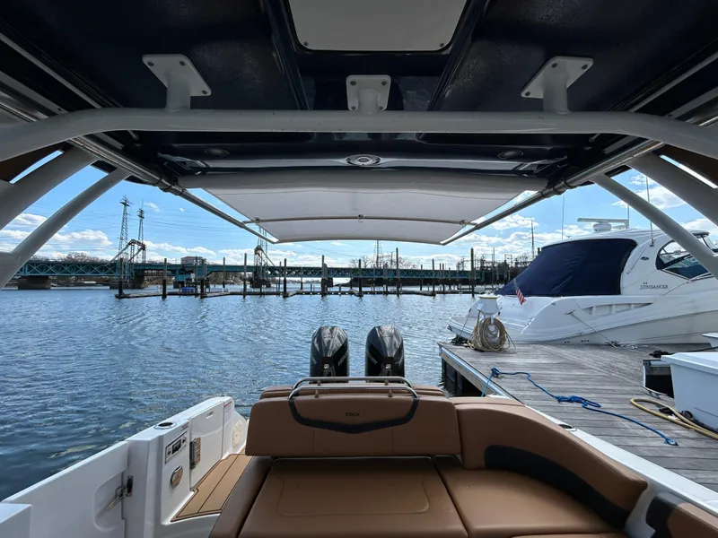 Slide: The Image of 2023 Chaparral 300 OSX boat interior view at marina with water and dock. - 7