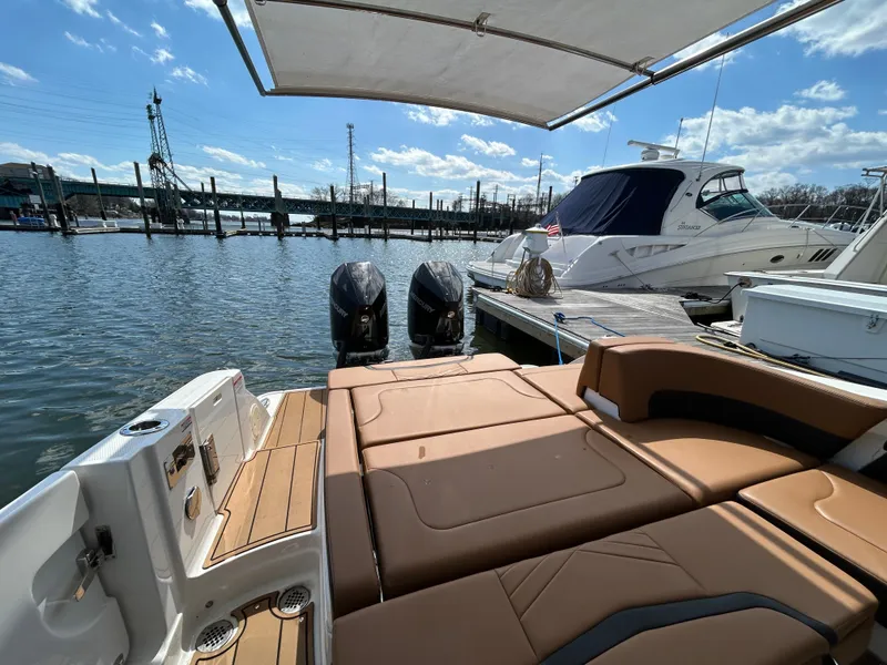 Slide: The Image of 2023 Chaparral 300 OSX boat with twin engines docked at marina under blue sky. - 8