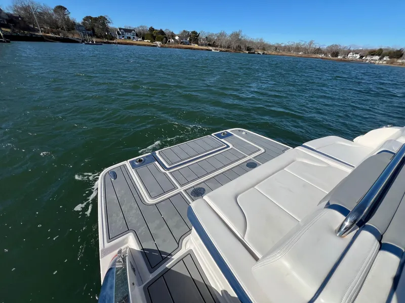 Slide: The Image of 2021 Chaparral 307 SSX boat on water, featuring a spacious deck and scenic shoreline view. - 10