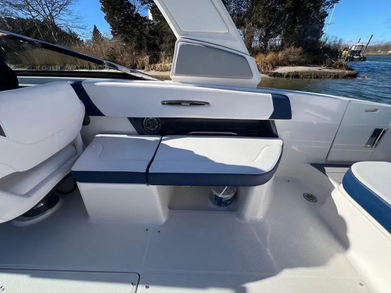 Slide: The Image of 2021 Chaparral 307 SSX boat interior with white and blue seating by the water. - 13