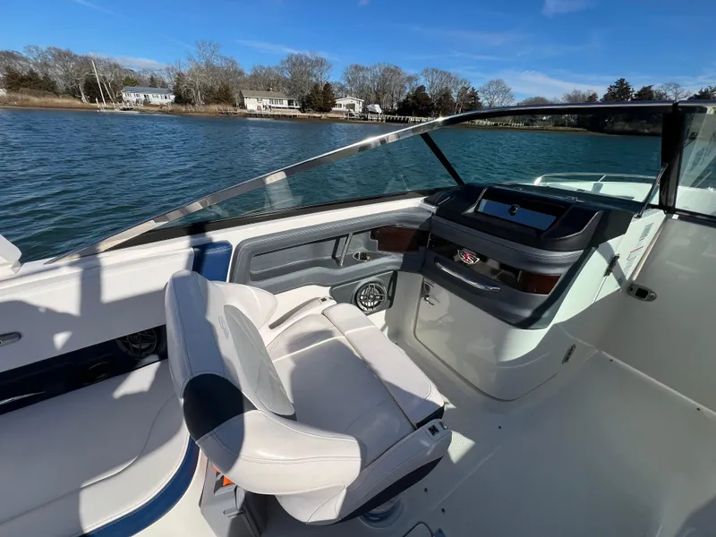 Slide: The Image of 2021 Chaparral 307 SSX boat interior with helm and seating, on a sunny day. - 15