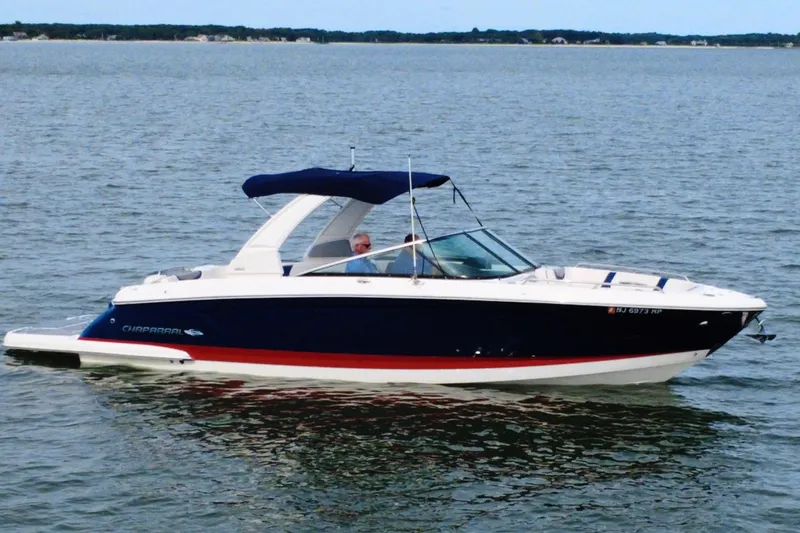 Slide: The Image of 2021 Chaparral 307 SSX boat cruising on calm waters with a blue canopy. - 4