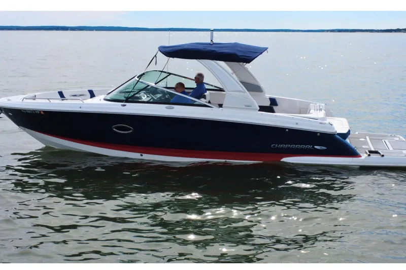Slide: The Image of 2021 Chaparral 307 SSX boat cruising on calm waters with two passengers. - 5