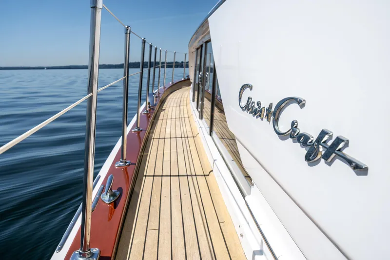 Slide: The Image of 1965 Chris-Craft 57 Constellation yacht deck with logo, cruising on calm waters. - 7