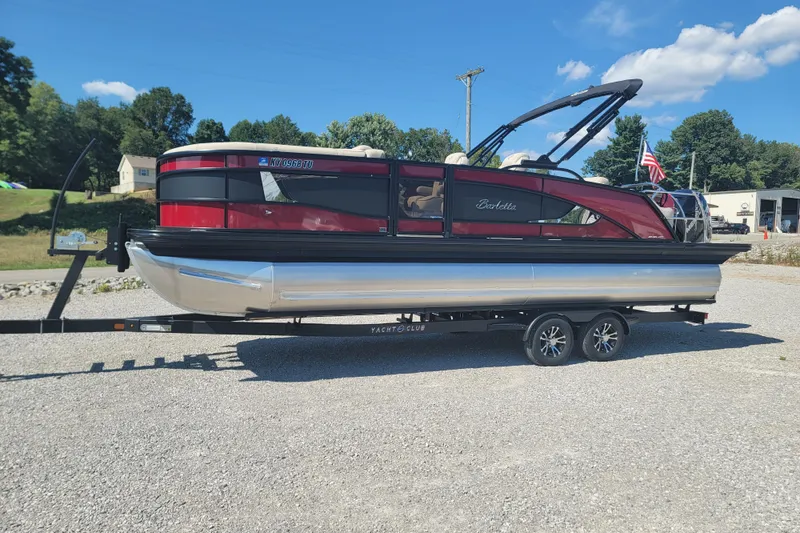 Slide: The Image of 2022 Barletta L23UC pontoon boat on trailer, parked outdoors under blue sky. - 0