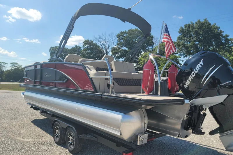 Slide: The Image of 2022 Barletta L23UC pontoon boat with Mercury engine on trailer, American flag displayed. - 10