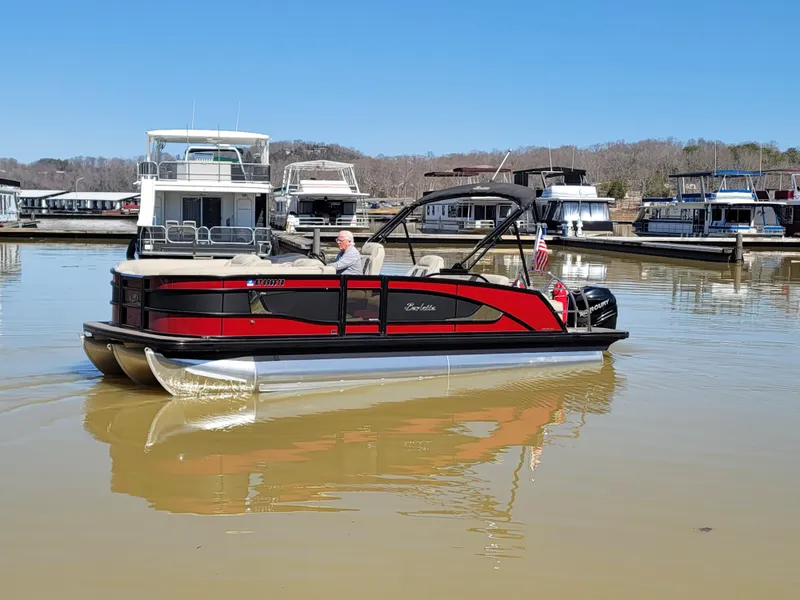 Slide: The Image of 2022 Barletta L23UC pontoon boat on a calm lake near a marina. - 48