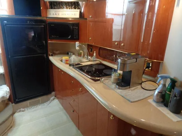 Slide: The Image of 1999 Sea Ray 400 Sundancer yacht kitchen with appliances and wooden cabinetry. - 13