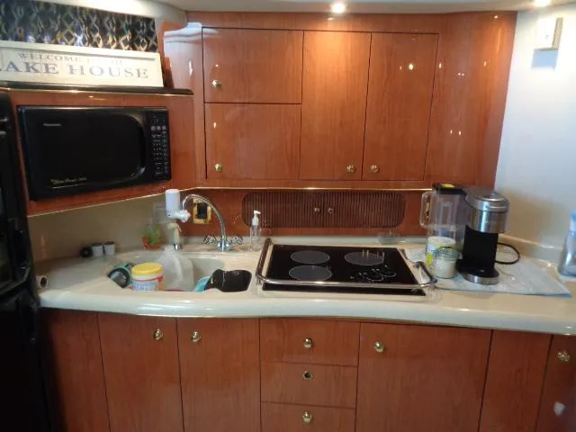 Slide: The Image of 1999 Sea Ray 400 Sundancer kitchen with wooden cabinets, microwave, and stovetop. - 16