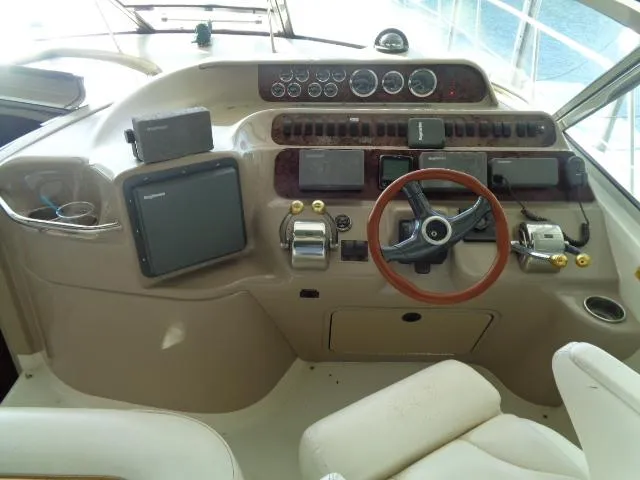 Slide: The Image of 1999 Sea Ray 400 Sundancer helm with steering wheel, gauges, and navigation equipment. - 19
